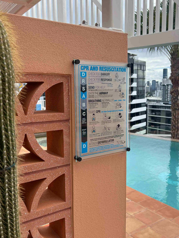 CPR and rescue information sign on a pool deck with a city skyline view.